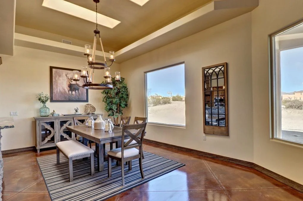 Dining room with polished concrete floors, coffered ceiling, and large windows overlooking desert landscape