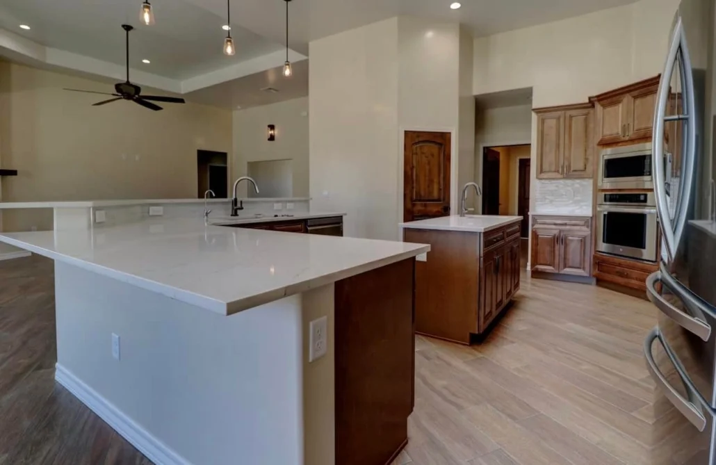 Kitchen with cherry cabinets, white quartz countertops, stainless steel appliances, and wood flooring