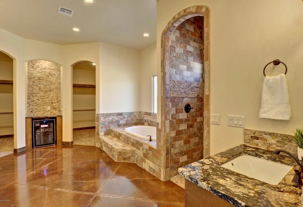 Master bathroom with stone tile shower, granite counters, soaking tub, and polished concrete floors