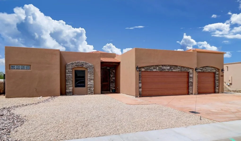 Stucco home with stone-accented entry and dual garage doors, concrete driveway