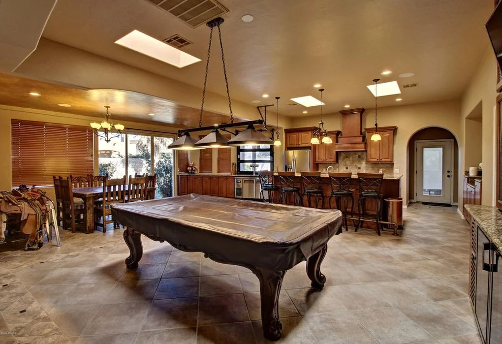 Large entertainment room with pool table, wood cabinetry, concrete flooring, and integrated kitchen