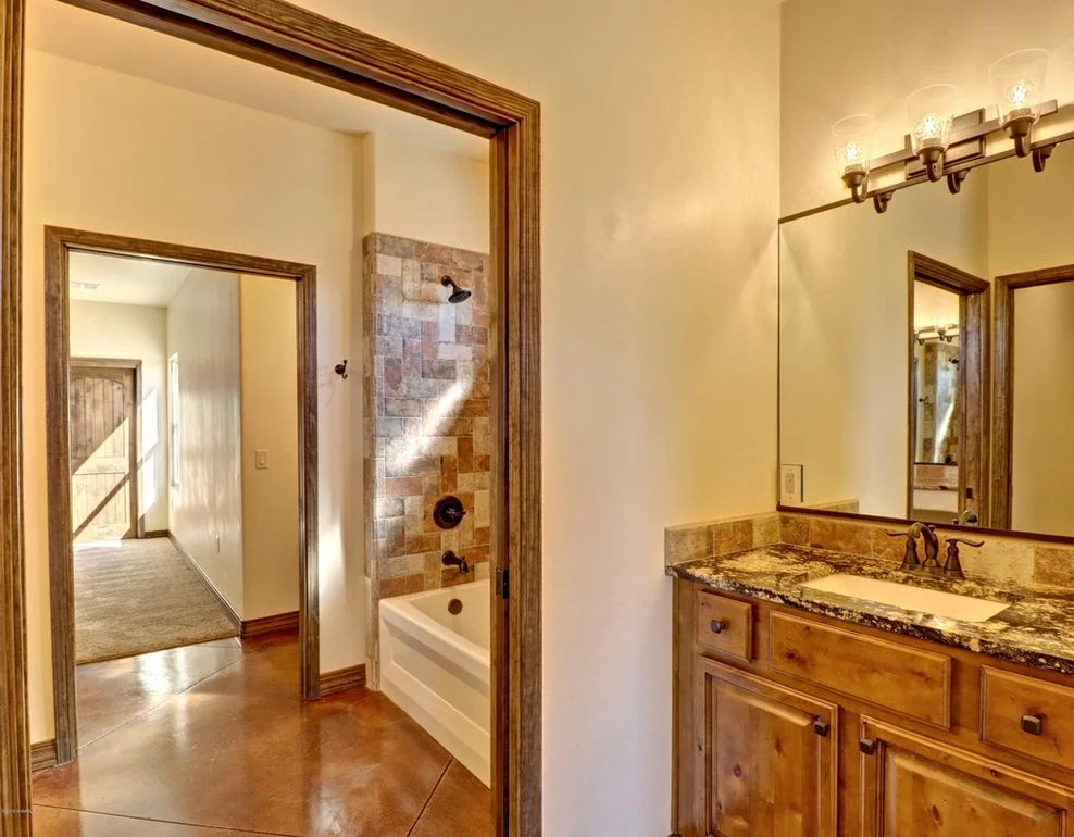 Master bathroom with granite counters, tile shower, wood cabinets, and polished concrete floors