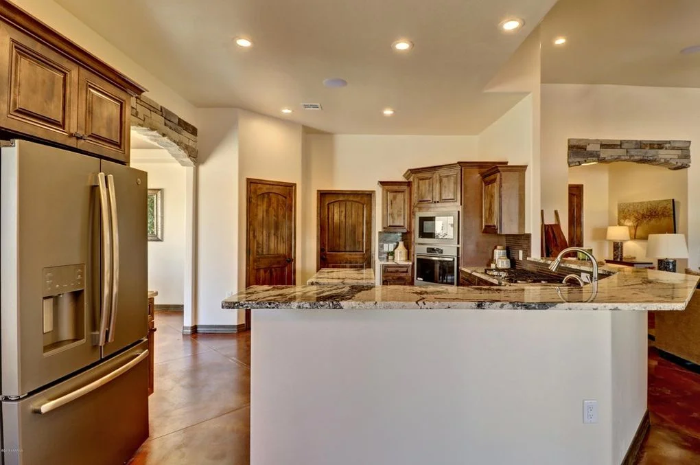Kitchen with granite island, wood cabinetry, stainless steel appliances, and recessed lighting