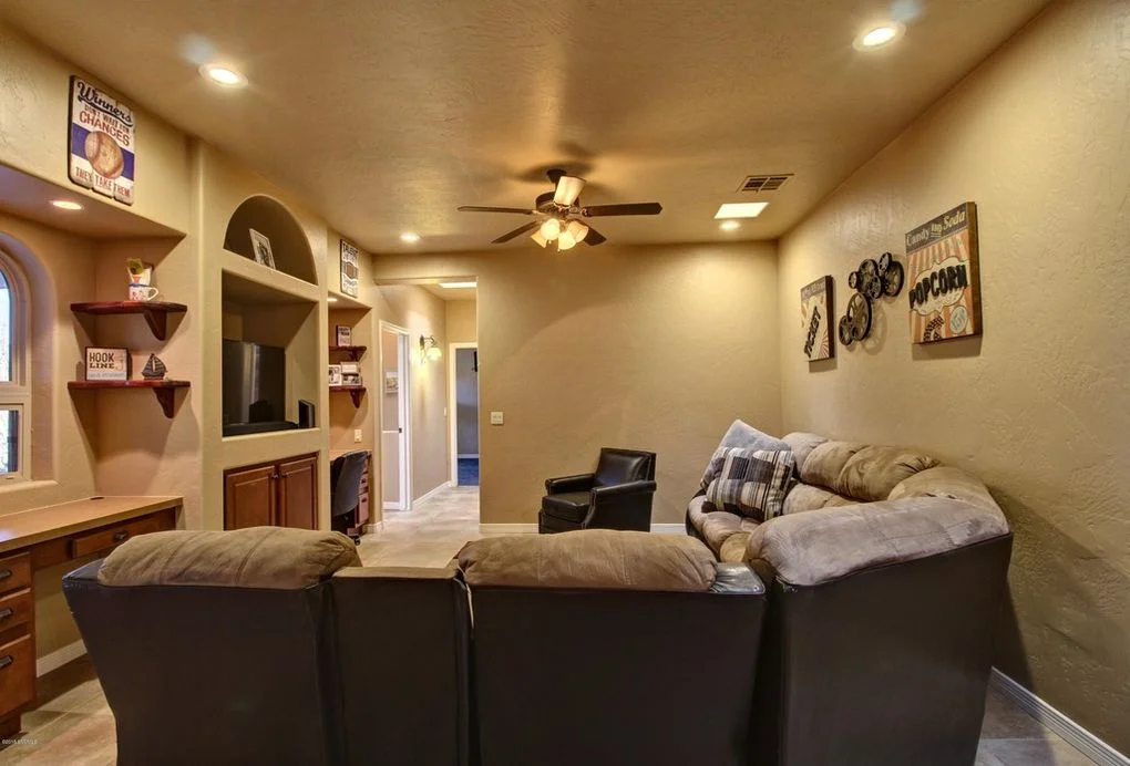 Den interior with dark leather seating, arched cabinetry, wet bar, and recessed lighting