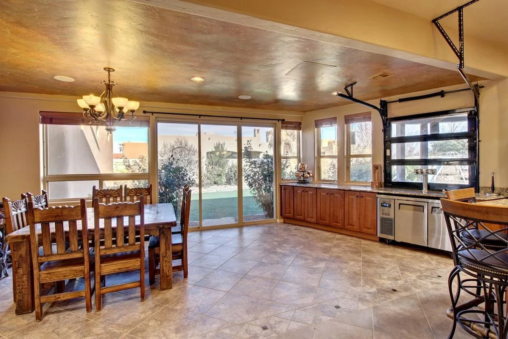 Open kitchen and dining room with travertine floors, wood cabinets, and glass patio doors