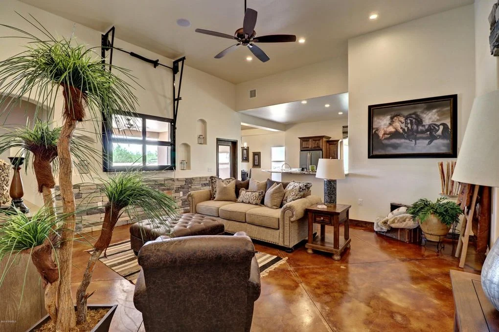 Open living room with polished concrete floors, vaulted ceiling, recessed lights, and architectural arches