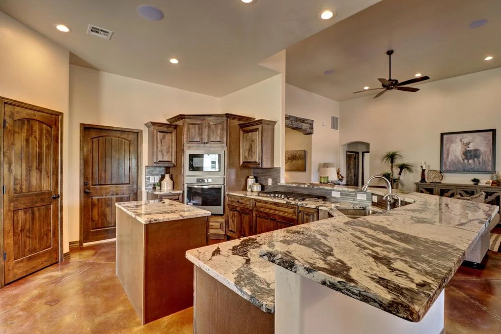 Dual granite islands with wood cabinetry, stainless steel appliances, and recessed lighting in open kitchen