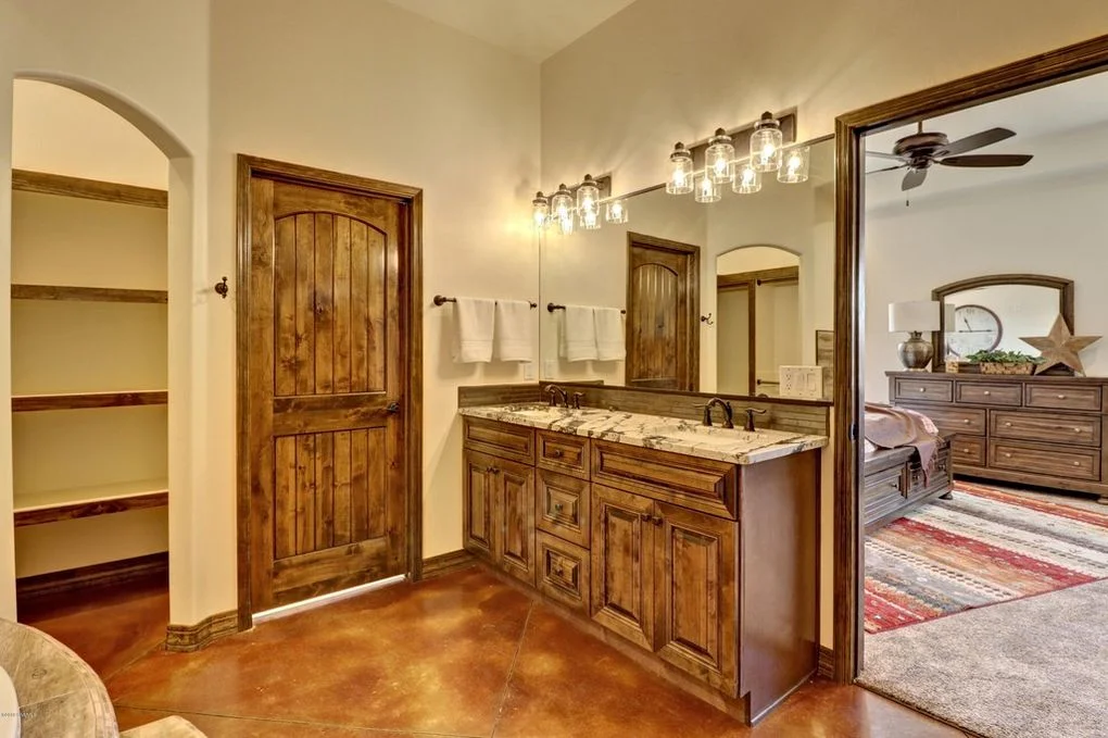 Master bathroom with knotty alder vanity, granite counters, arched doorways, and pendant lighting