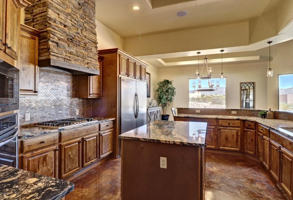 Kitchen with wood cabinets, granite counters, stone accent wall, and island with pendant lights