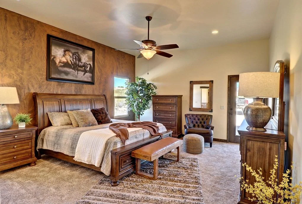 Master bedroom with wood furniture, textured accent wall, hardwood flooring, and ceiling fan
