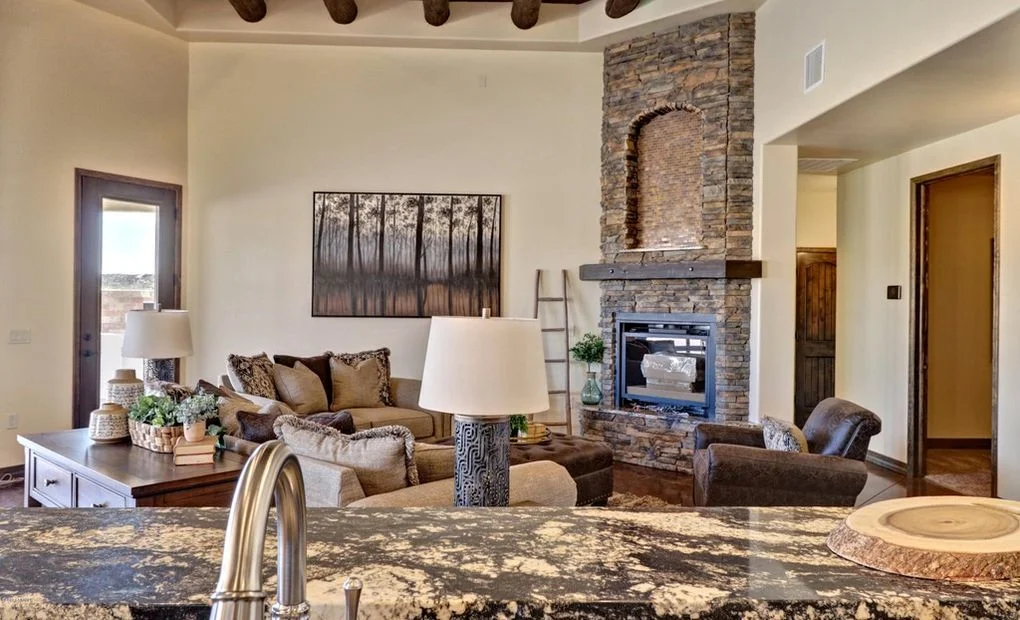 Family room with stacked stone fireplace, wood beams, granite counters, and custom furnishings