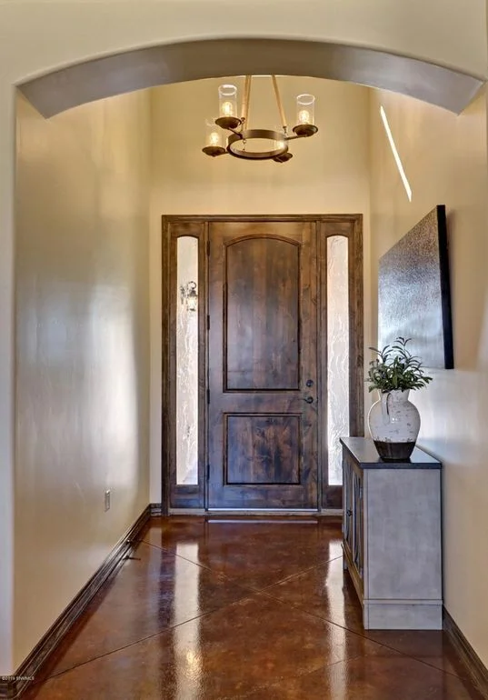 Entry foyer with arched ceiling, wooden door with sidelights, polished concrete floor, and pendant lighting