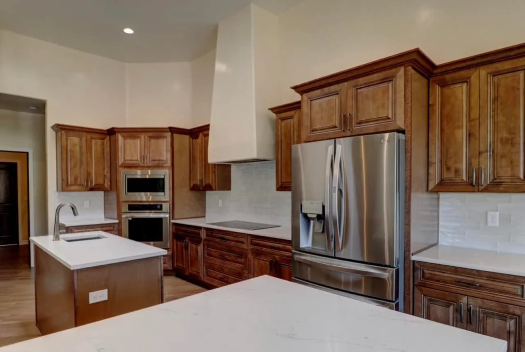Custom kitchen with wood cabinetry, stainless steel appliances, and white quartz counters
