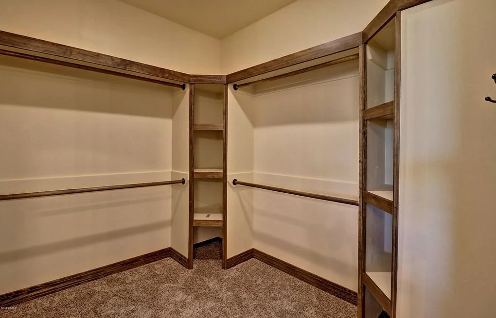 Walk-in closet with wood-framed shelving, dual hanging rods, and carpet flooring
