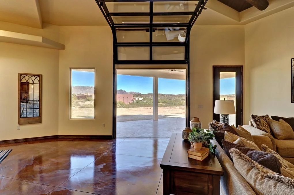 Polished concrete floors, glass doors, stucco walls, and desert views in modern family room