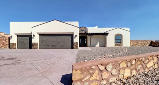 Modern stucco home with stone veneer, three-car garage, and stamped concrete driveway