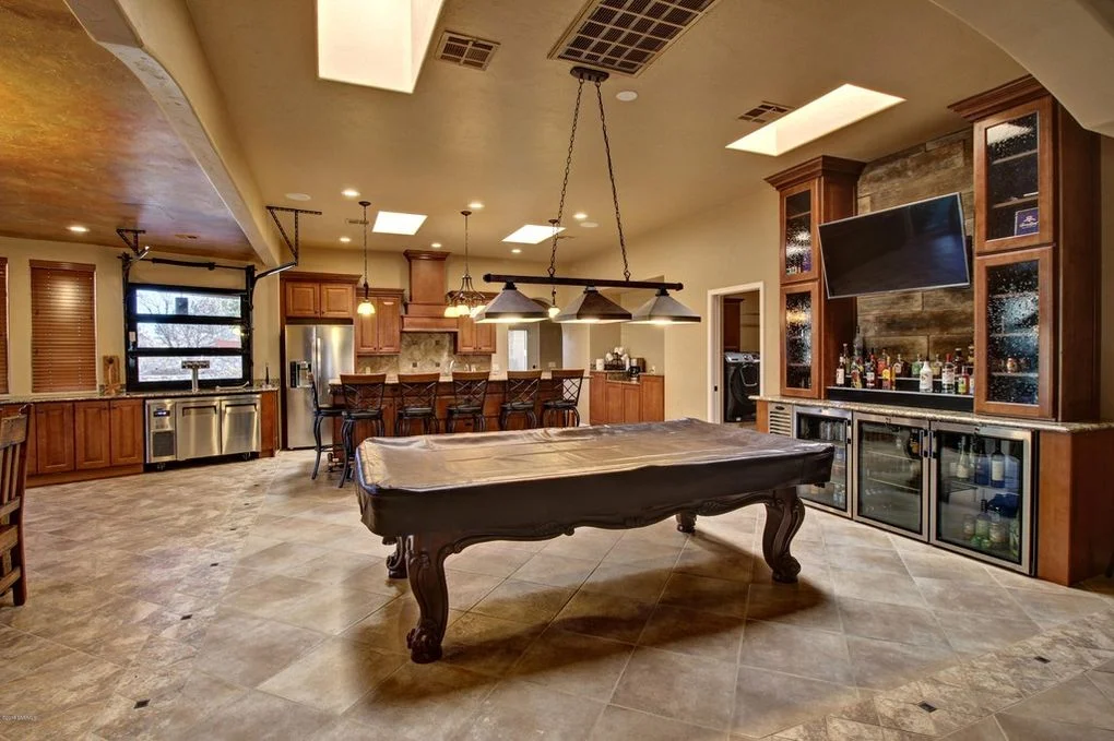 Entertainment room with travertine flooring, wood cabinetry, wet bar, and pool table