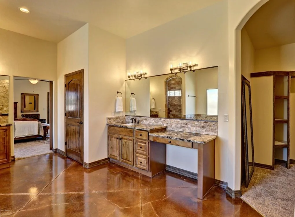 Double vanity with wood cabinetry, granite countertop, and tile backsplash in master bathroom