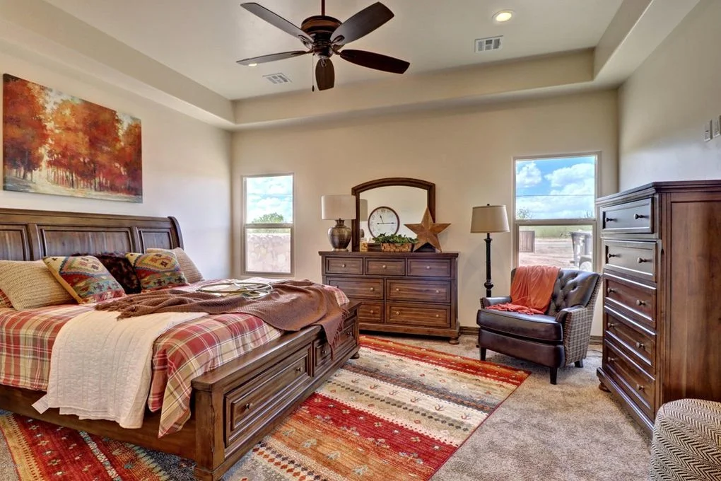 Master bedroom with tray ceiling, wood furniture, ceiling fan, and large windows