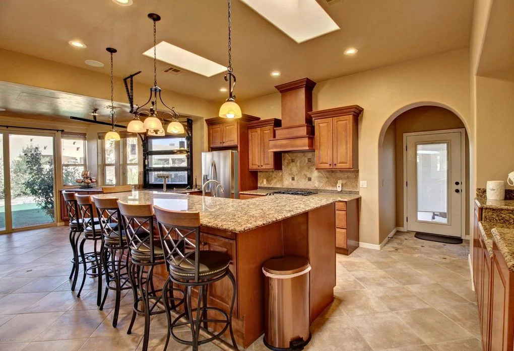 Custom cherry kitchen with granite island, stainless steel appliances, and pendant lighting