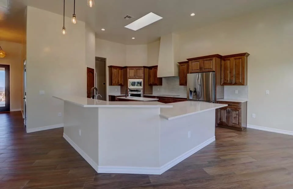 White quartz island with wood cabinetry, stainless appliances, and hardwood flooring in open kitchen